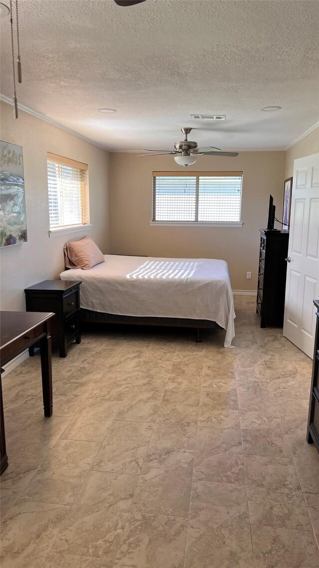 bedroom with a textured ceiling, baseboards, visible vents, and a ceiling fan