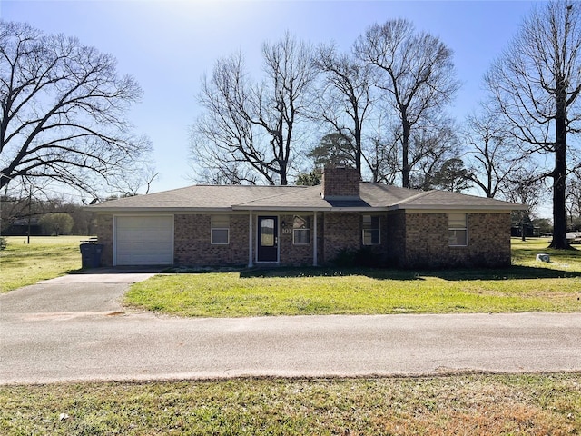 single story home with a garage, driveway, a chimney, a front lawn, and brick siding