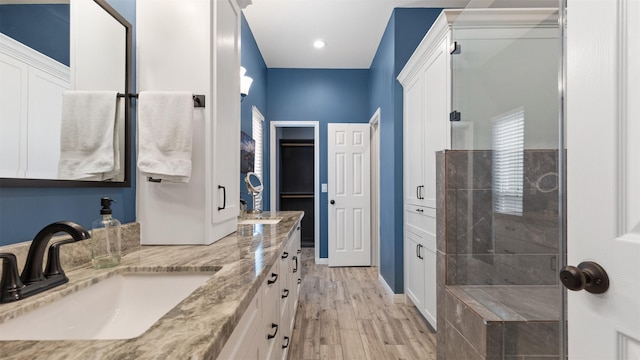 full bath featuring double vanity, recessed lighting, a stall shower, a sink, and wood finished floors