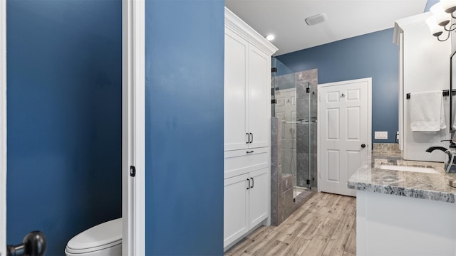 full bathroom with wood finished floors, a stall shower, vanity, and toilet