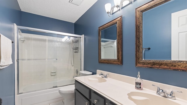 bathroom with toilet, a textured ceiling, combined bath / shower with glass door, and a sink