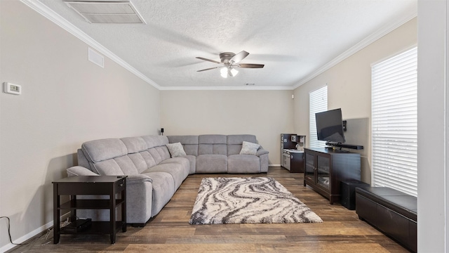 living room featuring a textured ceiling, visible vents, wood finished floors, and ornamental molding