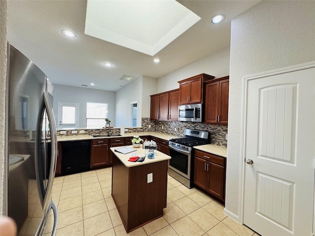 kitchen featuring light tile patterned floors, stainless steel appliances, a kitchen island, light countertops, and backsplash