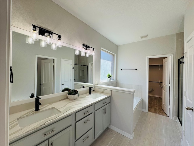 full bathroom with a spacious closet, a sink, visible vents, and a shower stall