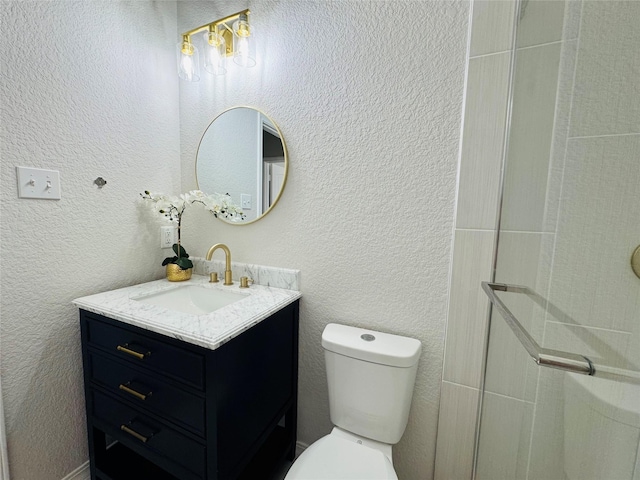 bathroom featuring toilet, a shower with door, vanity, and a textured wall