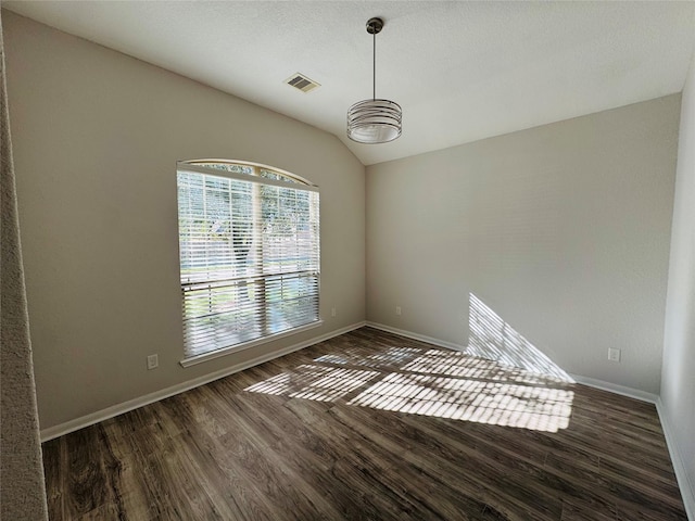 spare room featuring lofted ceiling, visible vents, baseboards, and wood finished floors