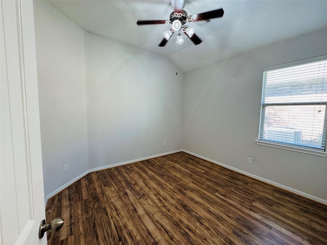 empty room with vaulted ceiling, dark wood-style flooring, a ceiling fan, and baseboards