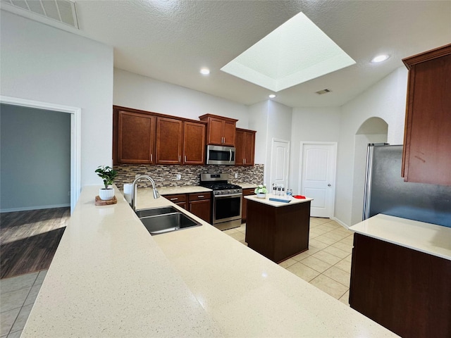 kitchen featuring light tile patterned floors, a sink, visible vents, appliances with stainless steel finishes, and backsplash