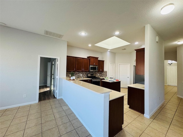 kitchen featuring a skylight, visible vents, light countertops, appliances with stainless steel finishes, and decorative backsplash