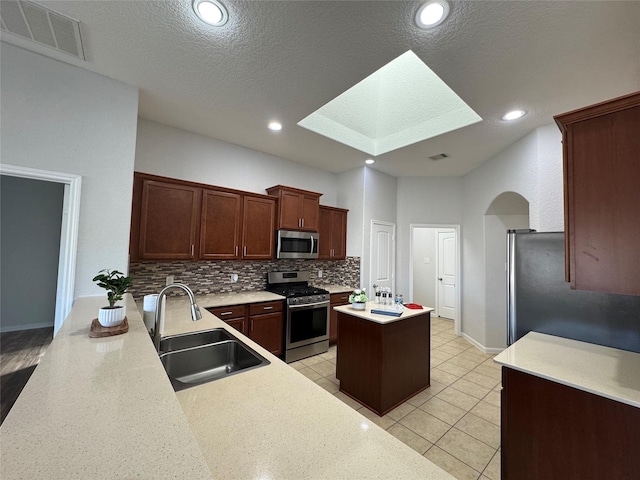 kitchen with a kitchen island, a sink, visible vents, appliances with stainless steel finishes, and tasteful backsplash