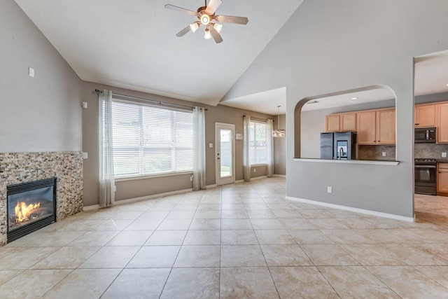 unfurnished living room featuring baseboards, a ceiling fan, a tiled fireplace, and light tile patterned flooring