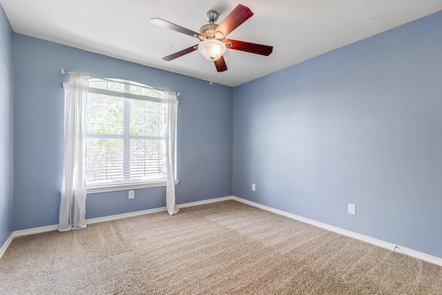 carpeted empty room featuring ceiling fan and baseboards