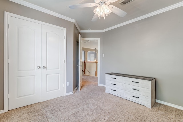 unfurnished bedroom with light carpet, visible vents, baseboards, ornamental molding, and a closet