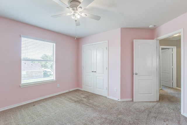 unfurnished bedroom with light carpet, ceiling fan, a closet, and baseboards