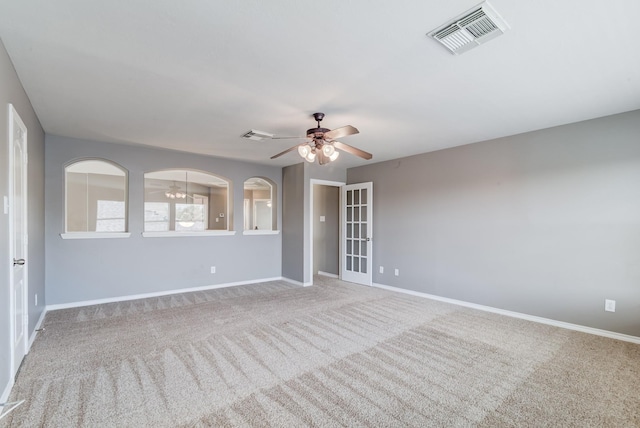 carpeted spare room featuring ceiling fan, visible vents, and baseboards