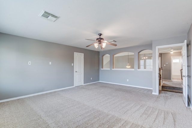 carpeted spare room featuring a ceiling fan, visible vents, and baseboards