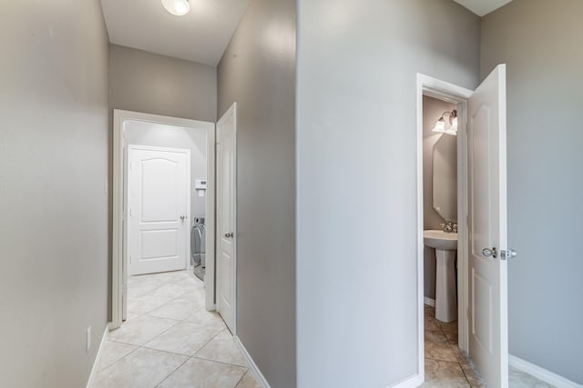 corridor with washer / clothes dryer, baseboards, and light tile patterned floors