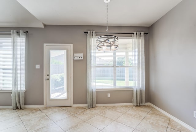 entryway with a wealth of natural light, light tile patterned flooring, and baseboards