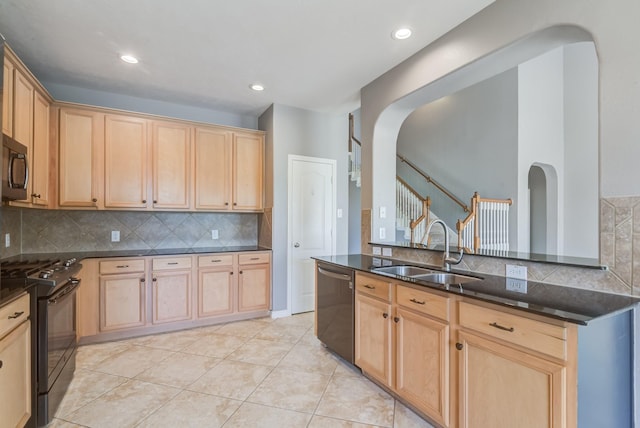 kitchen featuring arched walkways, light brown cabinets, a sink, dark stone countertops, and black appliances