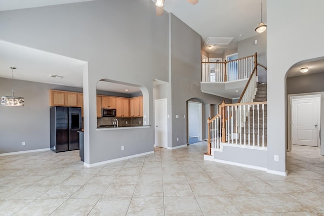 unfurnished living room with arched walkways, visible vents, and baseboards