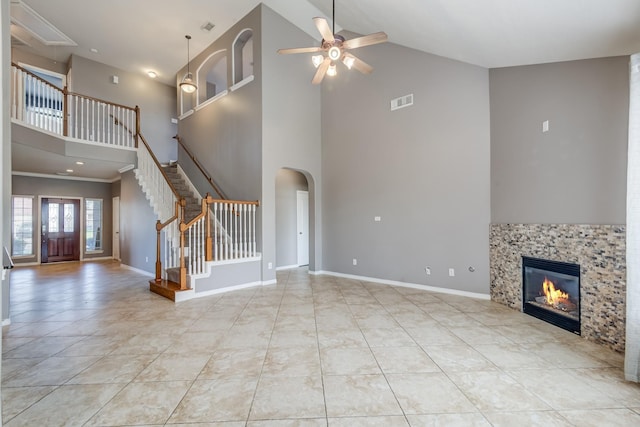 unfurnished living room with a fireplace, visible vents, stairway, ceiling fan, and baseboards