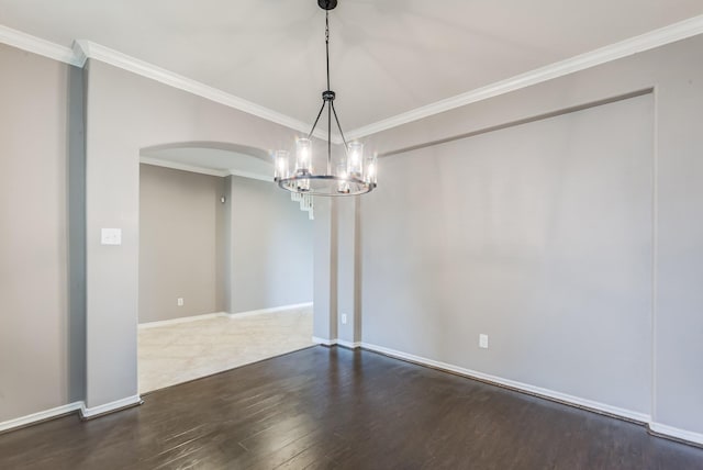 spare room with ornamental molding, arched walkways, baseboards, and wood finished floors