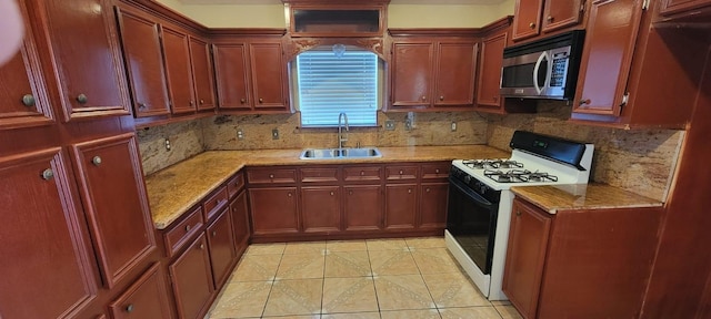 kitchen featuring light tile patterned floors, tasteful backsplash, stainless steel microwave, gas stove, and a sink