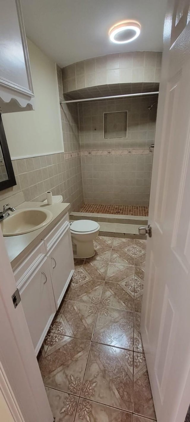 full bathroom with toilet, vanity, tile walls, a shower stall, and tile patterned floors