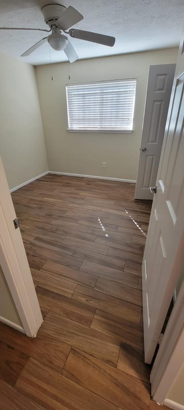 interior space with ceiling fan, a textured ceiling, baseboards, and wood finished floors