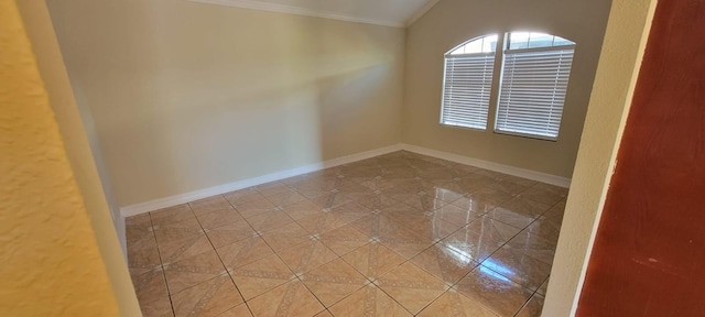 tiled spare room featuring lofted ceiling, baseboards, and crown molding