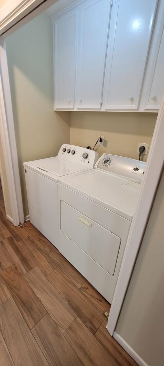 laundry area with light wood-style floors, cabinet space, and washer and clothes dryer