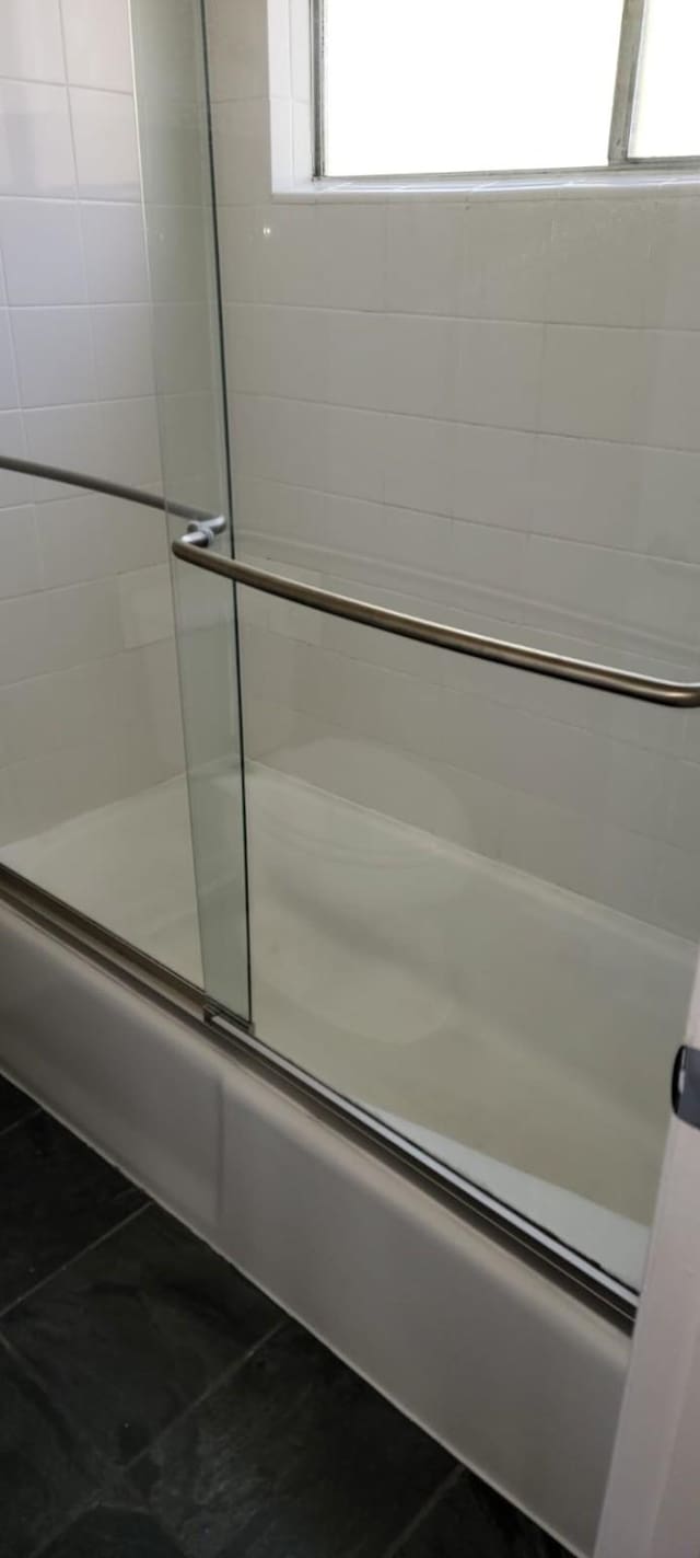 full bath featuring combined bath / shower with glass door and tile patterned floors