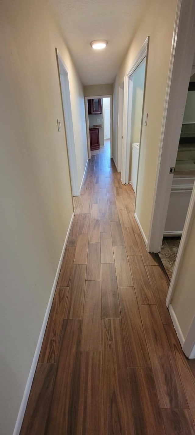 hallway featuring baseboards and wood finished floors