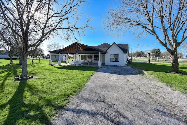 view of front facade featuring driveway, a front lawn, and fence