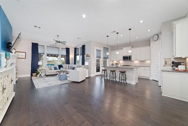 living room with visible vents, baseboards, ceiling fan, dark wood-type flooring, and recessed lighting