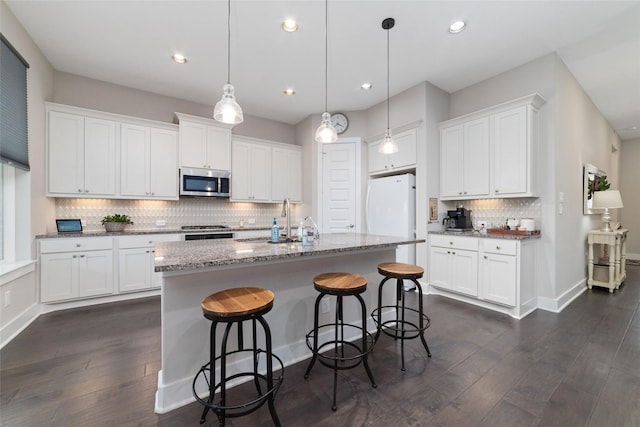 kitchen with freestanding refrigerator, stainless steel microwave, a sink, and white cabinetry