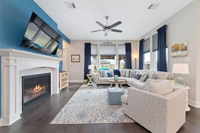 living room with a tiled fireplace, wood finished floors, visible vents, and baseboards