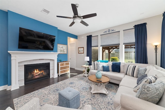 living room with a tiled fireplace, wood finished floors, visible vents, and baseboards