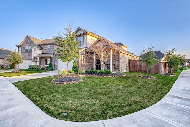 view of front of home featuring concrete driveway, brick siding, fence, and a front lawn