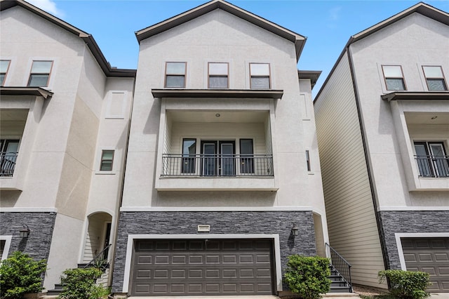 multi unit property with a garage, stone siding, driveway, and stucco siding