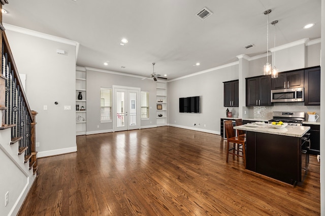 kitchen with dark wood-style floors, stainless steel appliances, visible vents, ornamental molding, and ceiling fan