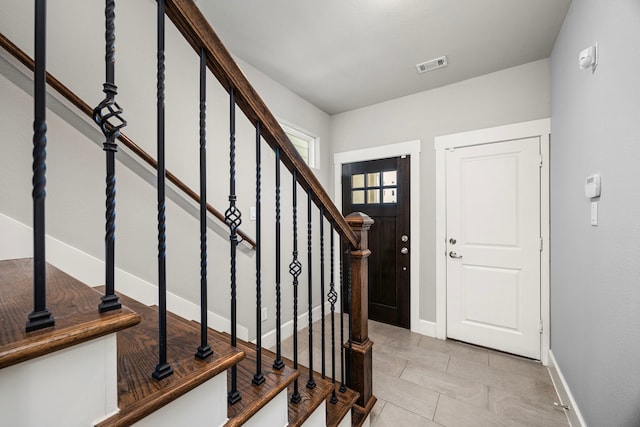 entryway with visible vents, stairway, baseboards, and light tile patterned floors