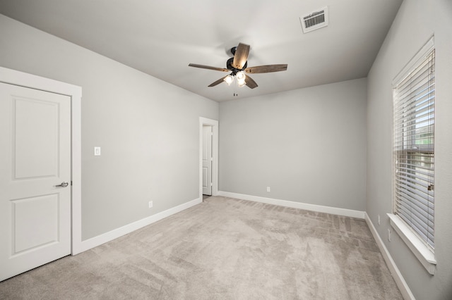 unfurnished room featuring baseboards, a ceiling fan, visible vents, and light colored carpet