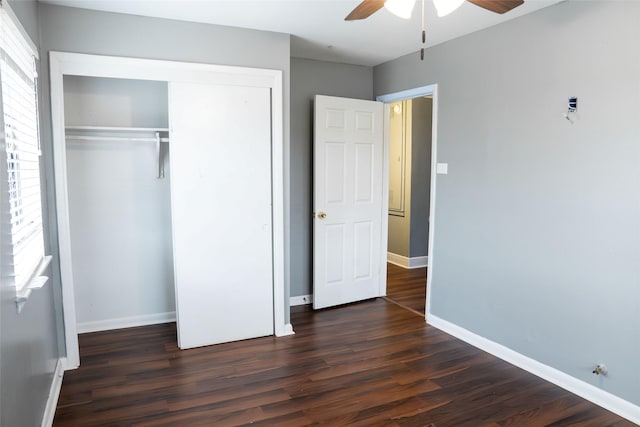 unfurnished bedroom with dark wood-style flooring, a closet, a ceiling fan, and baseboards