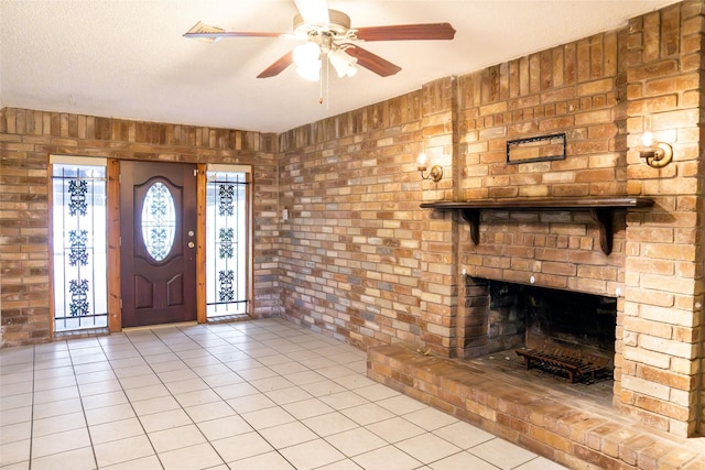 foyer with a ceiling fan, a fireplace, a textured ceiling, and light tile patterned floors