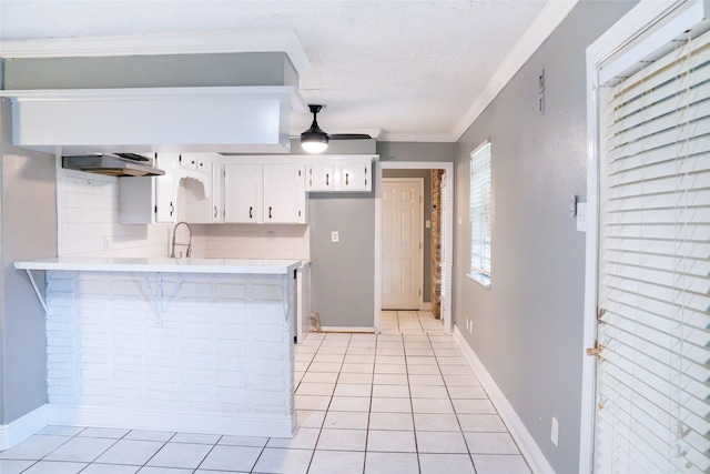 kitchen with a peninsula, light countertops, a ceiling fan, and light tile patterned flooring