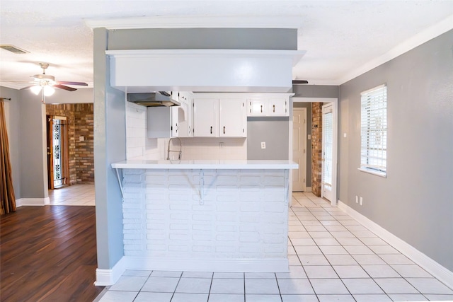 kitchen featuring visible vents, light countertops, ceiling fan, a sink, and a peninsula