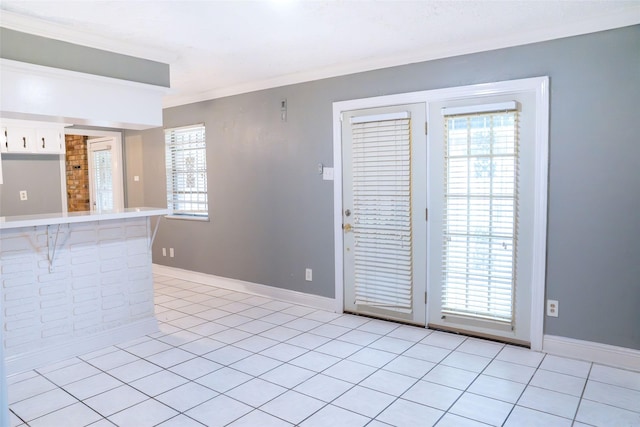 interior space featuring light tile patterned floors, ornamental molding, baseboards, and a healthy amount of sunlight