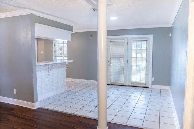 interior space with light tile patterned floors, decorative columns, ornamental molding, and a wealth of natural light