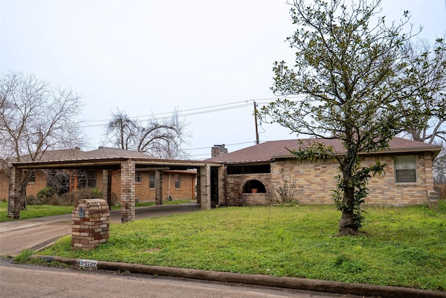 view of front facade featuring a front yard, a chimney, and brick siding